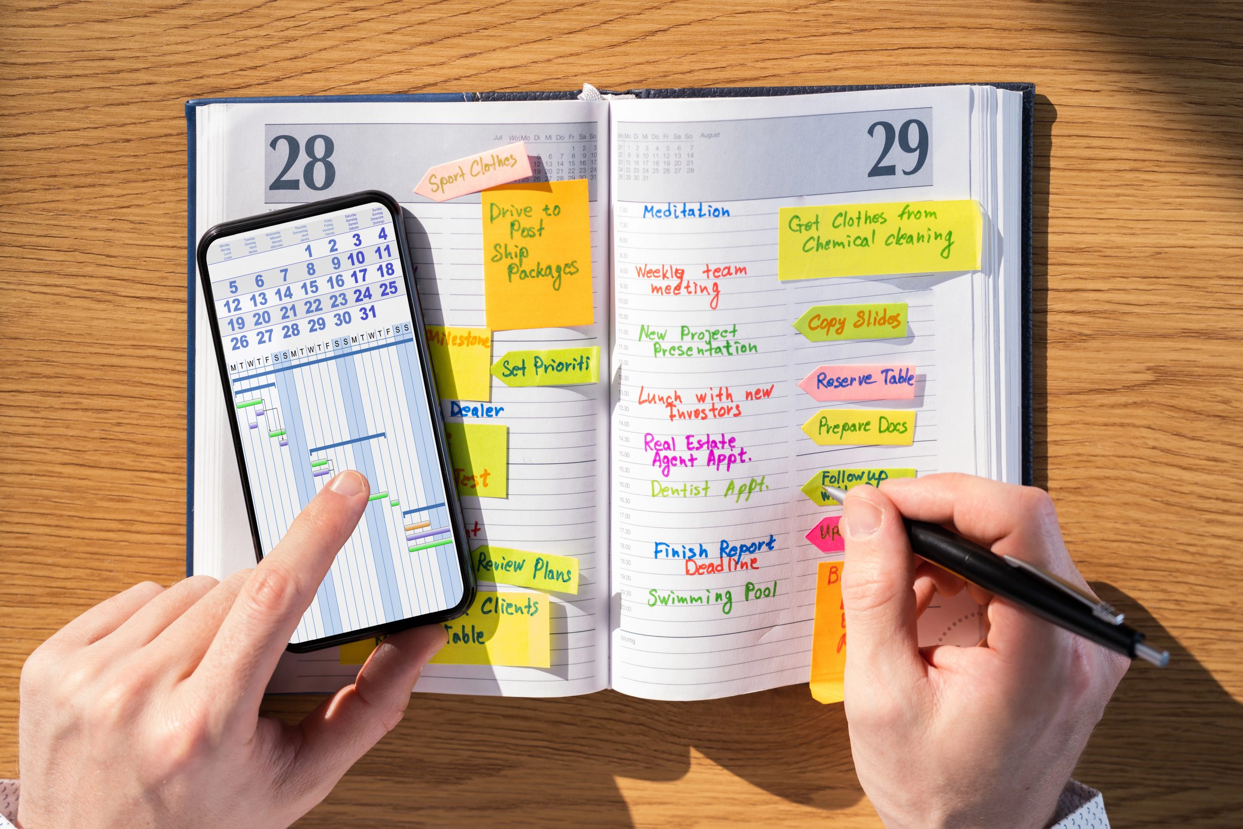 voller Terminkalender mit Post-Its und Wochenplanung mit Handy schreiben